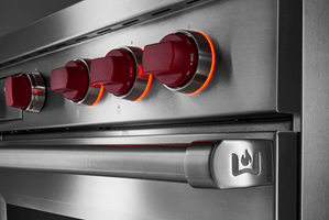 La cuisinière mixte Wolf présente des lumières de halo autour des boutons rouges lorsqu'elle est en fonctionnement