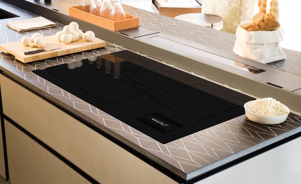 La surface de cuisson à induction Wolf 36 po de style contemporain (CI36560C/B) est encastrée dans les plans de travail de la cuisine, présentant un motif symétrique continu.