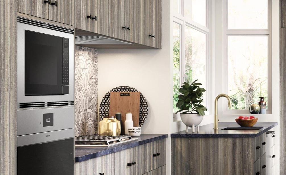 Four à micro-ondes standard Wolf 24 po (MS24) présenté dans un design de cuisine rustique ouverte avec des planchers en béton à tons chauds et des armoires en panneaux de bois