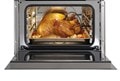 Interior view of an open Wolf 24" E Series Transitional Convection Steam Oven (CSO2450TE/S/T) displaying a perfectly cooked chicken with a probe in it