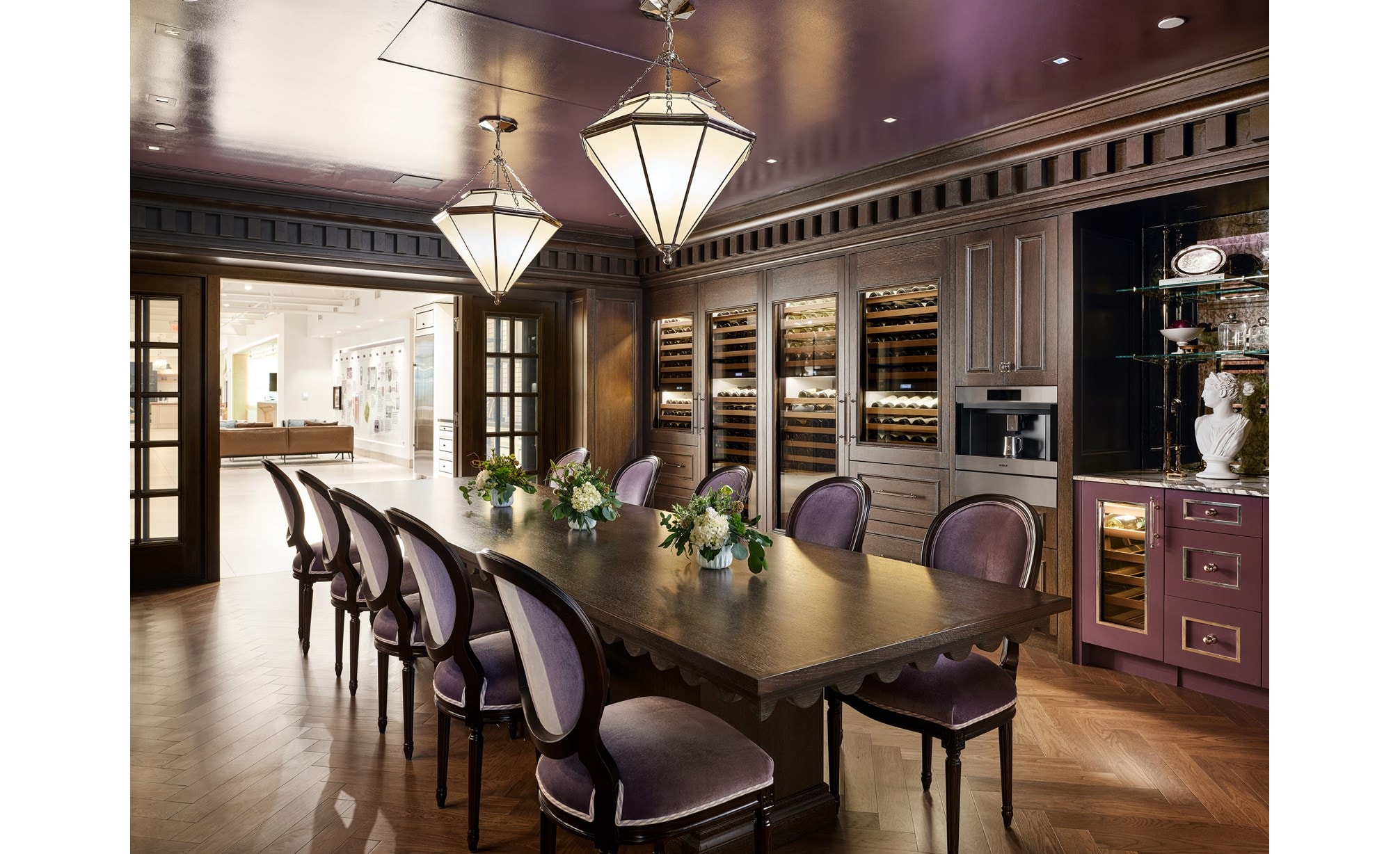 A fancy, luxury-styled kitchen with a brown wooden tabletop and light purple chairs with Sub-Zero wine refrigerators.