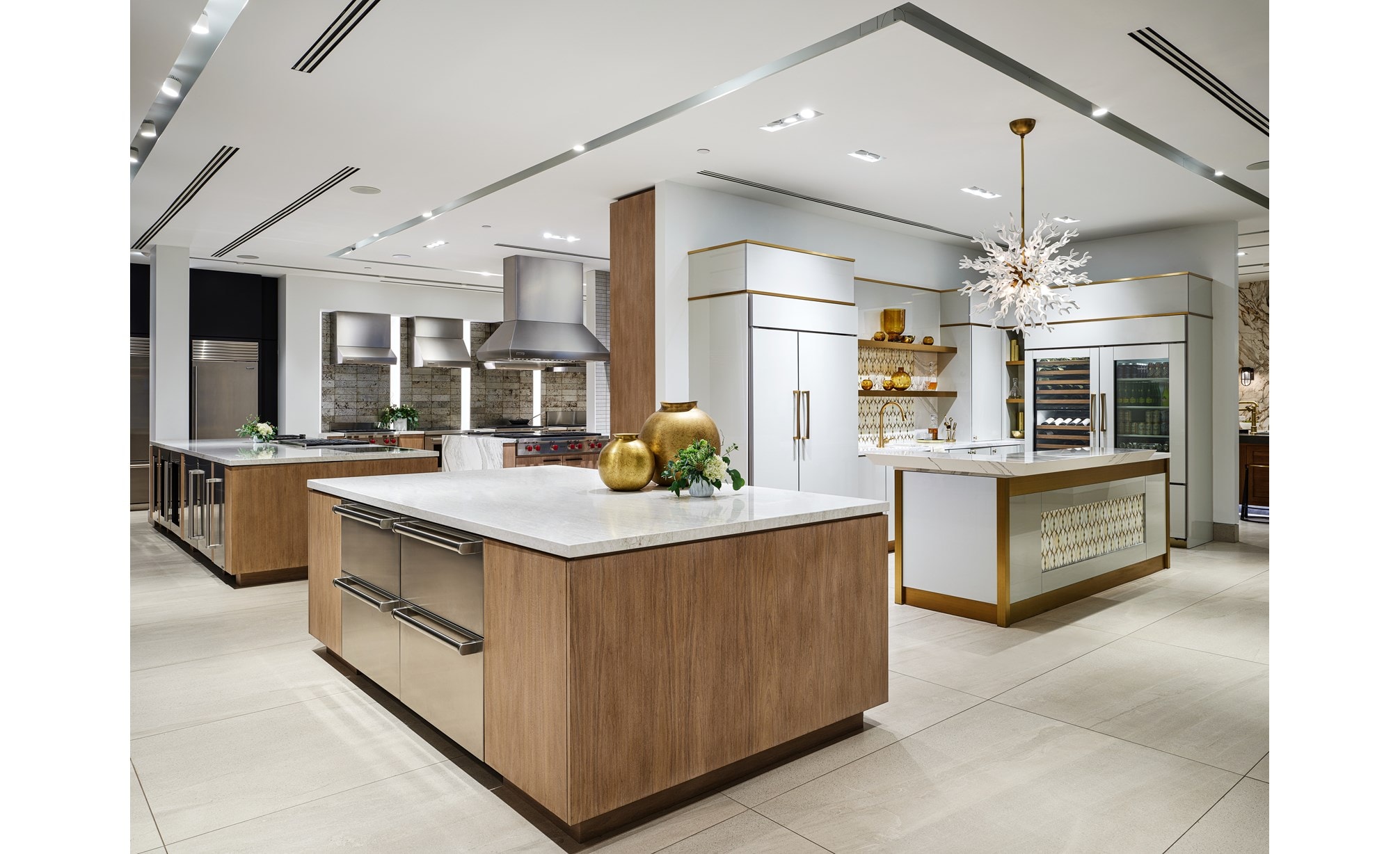 A white professional kitchen with white-marbled countertops and built-in Sub-Zero, Wolf, and Cove appliances