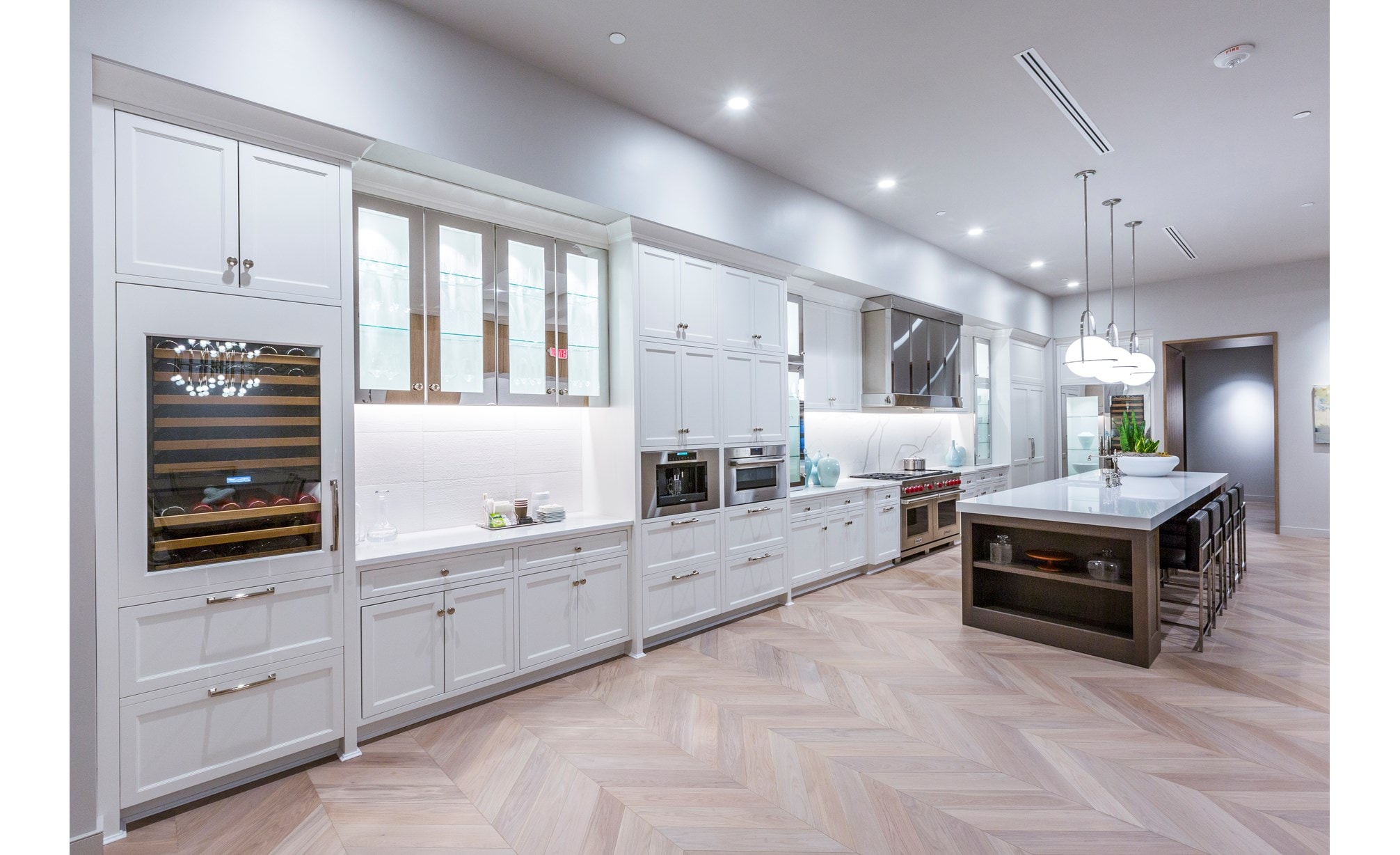 A white kitchen with many different installations and styles of Sub-Zero, Wolf, and Cove appliances. 