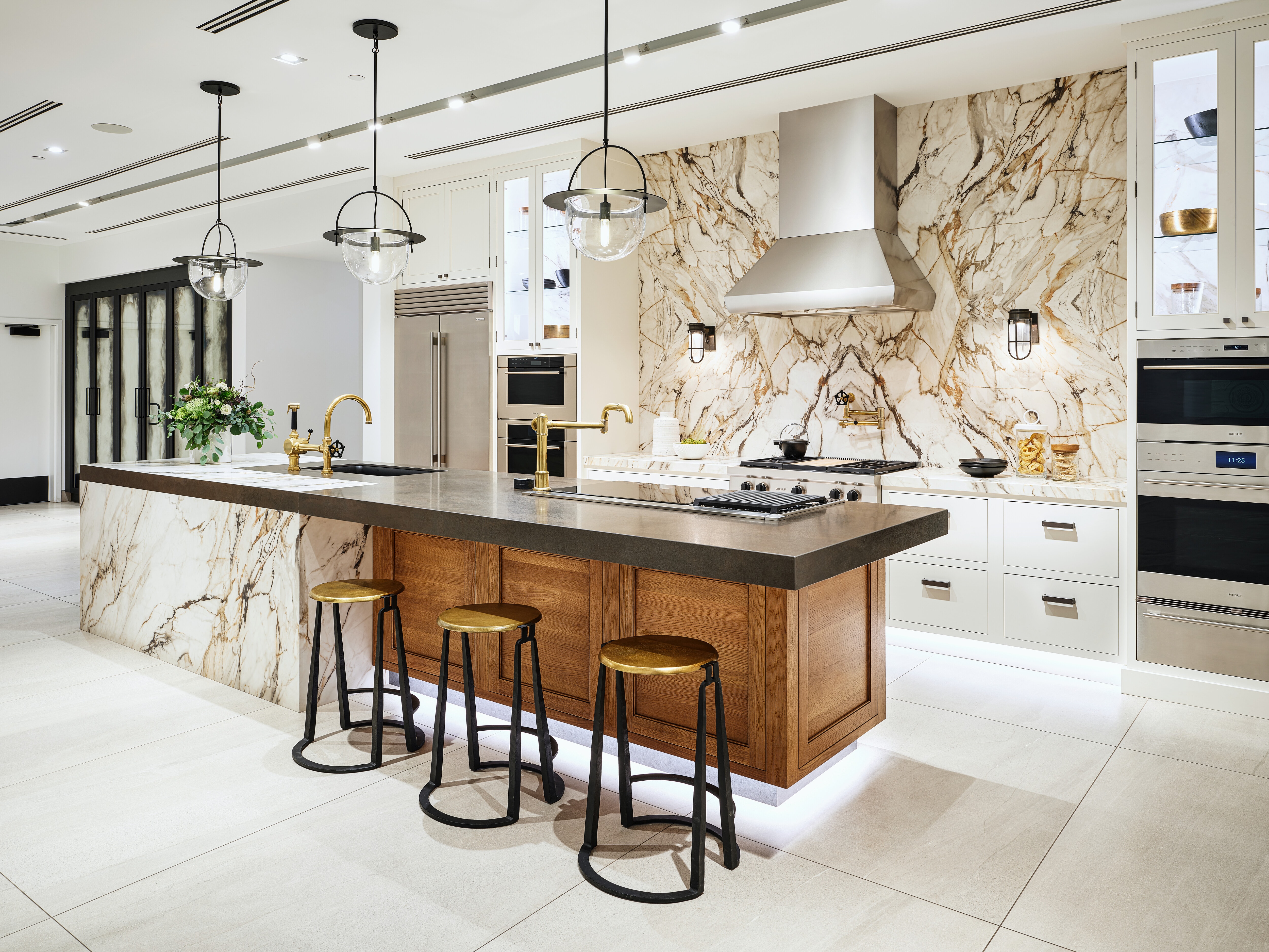 A white kitchen vignette with a black countertop featuring an array of Sub-Zero, Wolf, and Cove appliances.