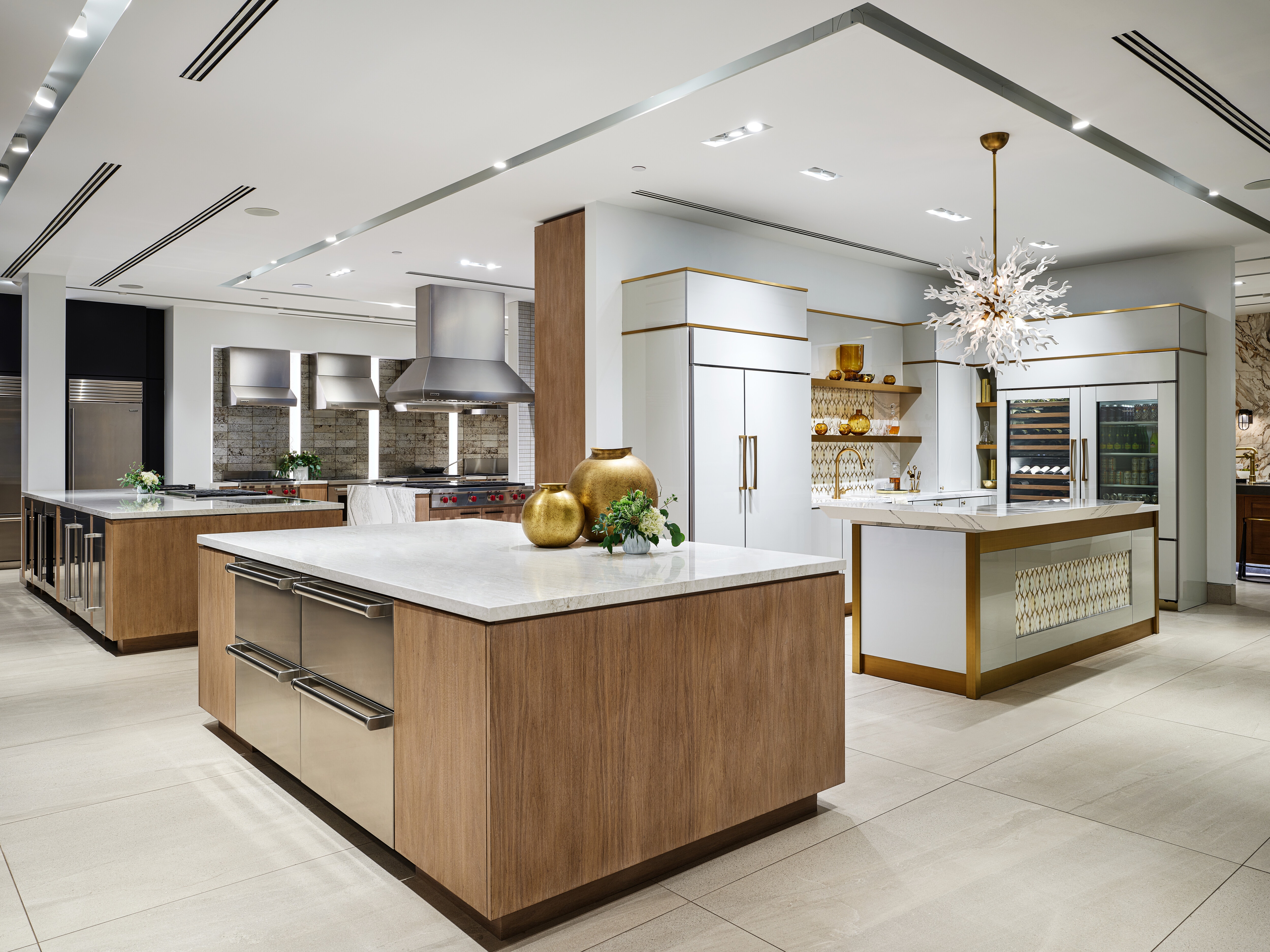 A white professional kitchen with white-marbled countertops and built-in Sub-Zero, Wolf, and Cove appliances