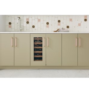 Frontal view of closed Sub-Zero 15" Designer Undercounter Beverage Center with Solid Door - Panel Ready (DEU1550B) shown in a row of tan custom cabinets