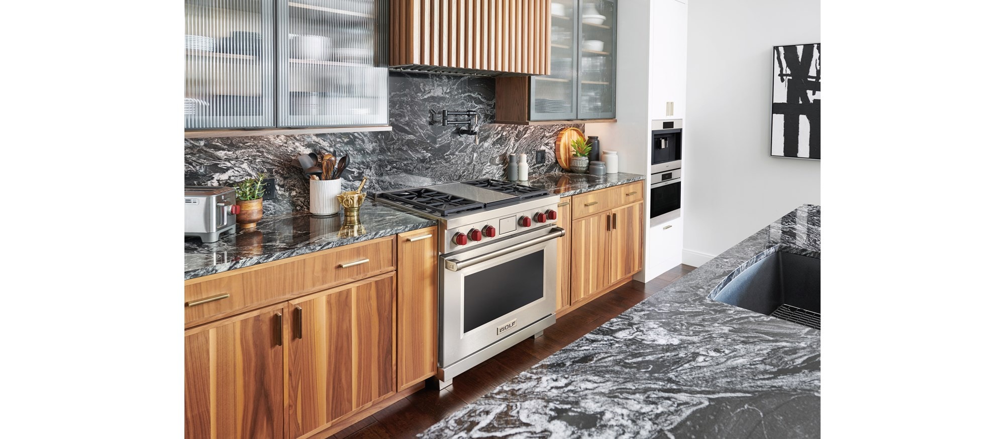 Wolf 36" Dual Fuel Range displayed in a modern kitchen condo design featuring custom cabinetry and rich marble countertops.