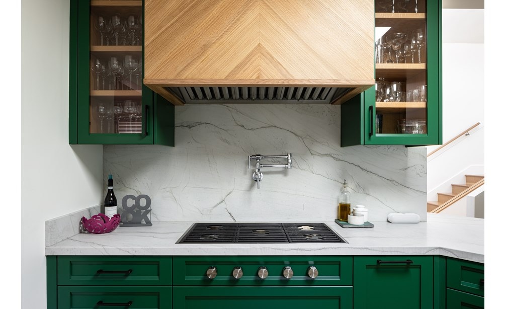Wolf 36-inch contemporary gas cooktop featured in small space stylish kitchen with green cabinets and marble backsplash.