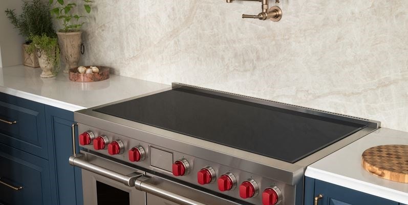 Wolf 36-inch Contemporary Induction Cooktop (CI36560T) featuring sleek black glass surface installed flush in a modern Mediterranean kitchen design.