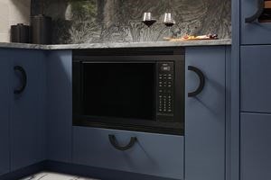 Wolf Standard Swing Microwave flushed with the cabinetry of a luxury, blue-colored kitchen.