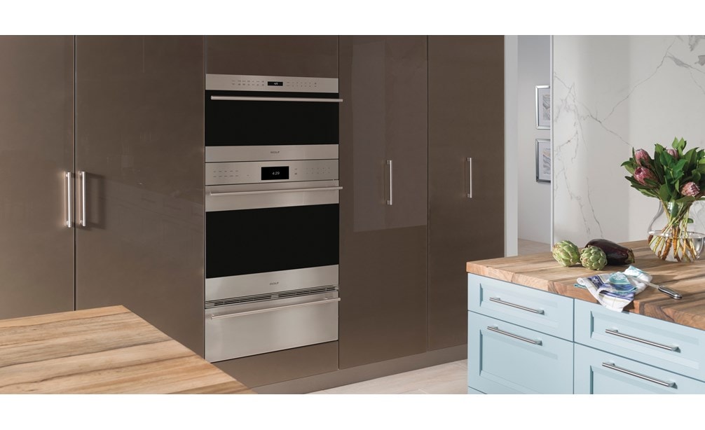 The Wolf 30" E series Transitional Drop-Down Door Microwave Oven (MDD30TE/S/TH) shown set flush in smooth floor to ceiling cabinetry