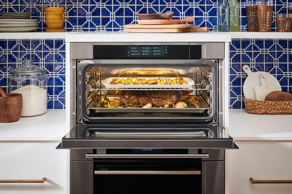 Wolf Convection Steam Oven displayed in a Mediterranean style kitchen design featuring blue tile backsplash and open kitchen shelves.