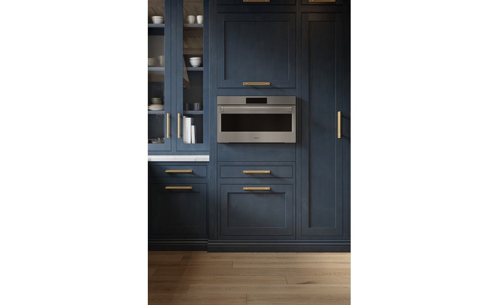 A close-up look at the Wolf 30" E Series Professional Speed Oven - SPO3050/PE/S/P built-in next to blue cabinetry