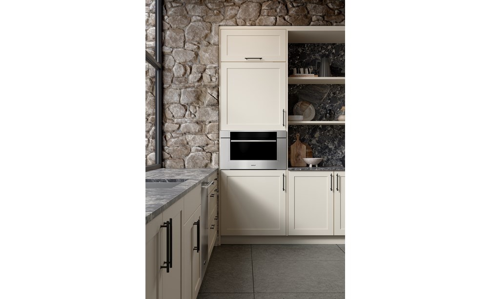 A close-up of the Wolf Transitional Speed Oven inside a brick kitchen with white-colored cabinets