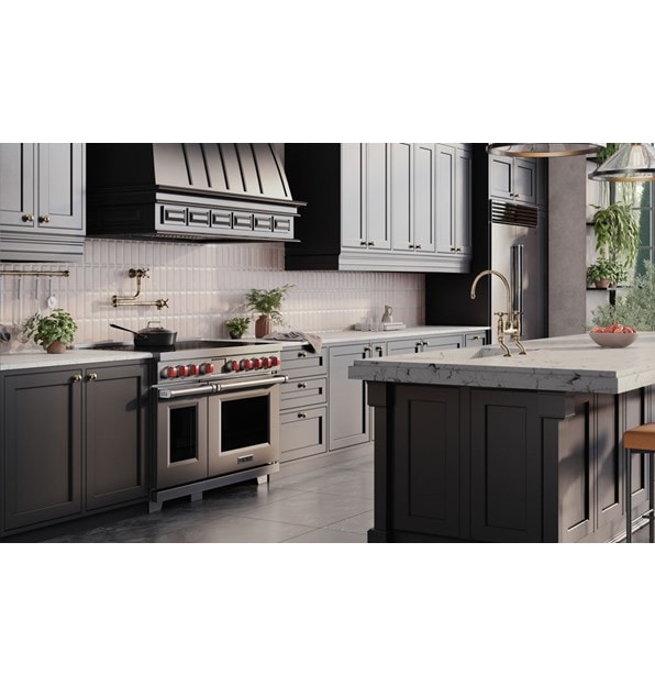 Wolf Professional Induction Range with stainless accent oven door and iconic red knobs shown in a modern bohemian kitchen design featuring custom grey kitchen cabinets enclosing a Wolf Pro Hood Liner.