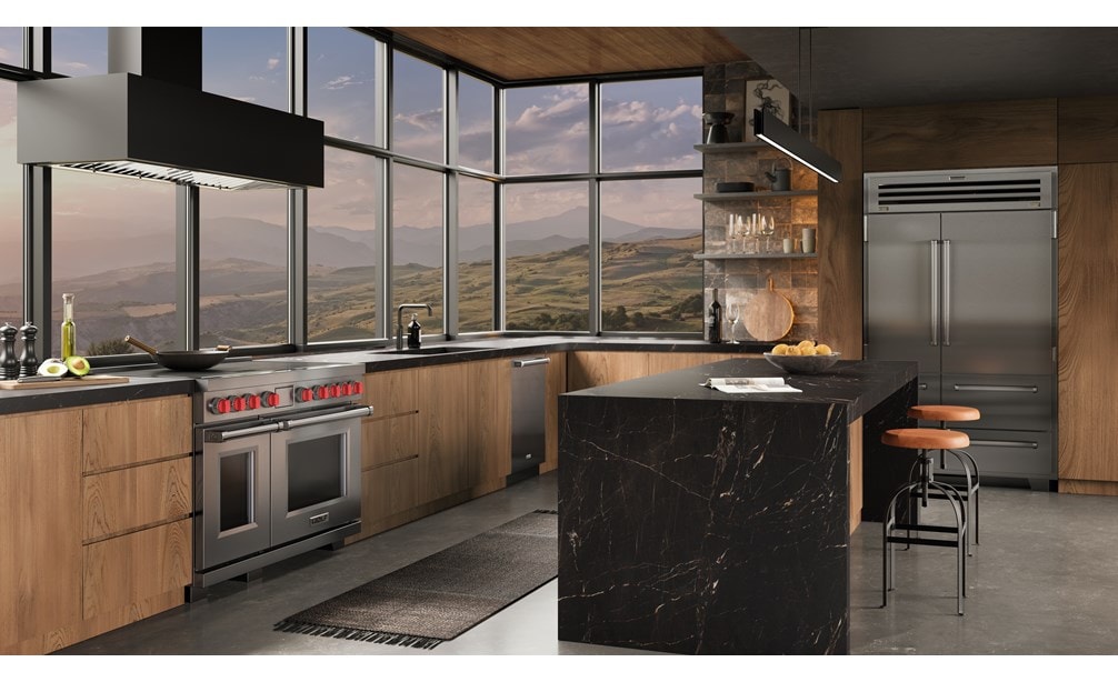 Wolf 48 Inch Professional Induction Range with matching stainless steel Sub-Zero 48 Inch PRO Refrigerator Freezer featured in an ambient  industrial kitchen design with a wall of windows overlooking an expansive mountain range.