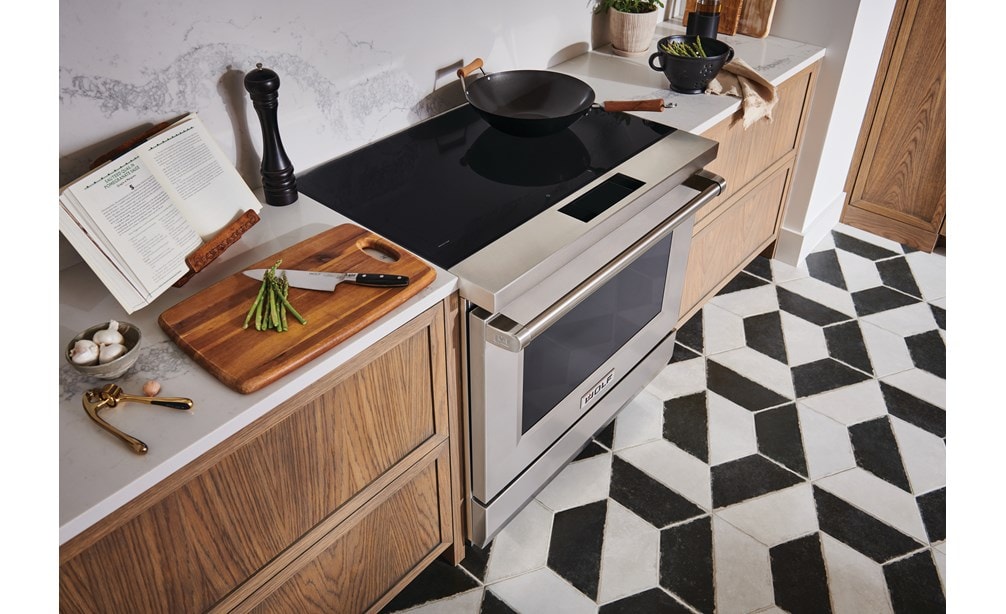 Wolf 36" Professional Induction Range (IR36550/S/P) with a wok pan on its ceramic black surface next to cutting board with asparagus.