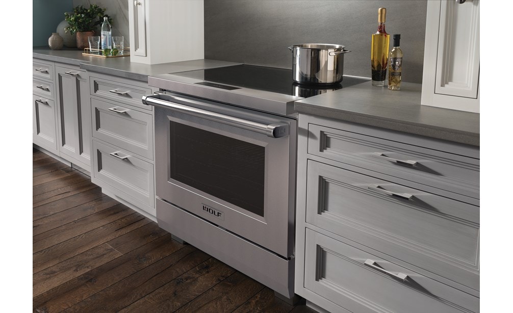 Wolf 36" Professional Induction Range (IR36550/S/P) featured in gray cabinetry with a stainless steel pot on it ceramic black glass surface.
