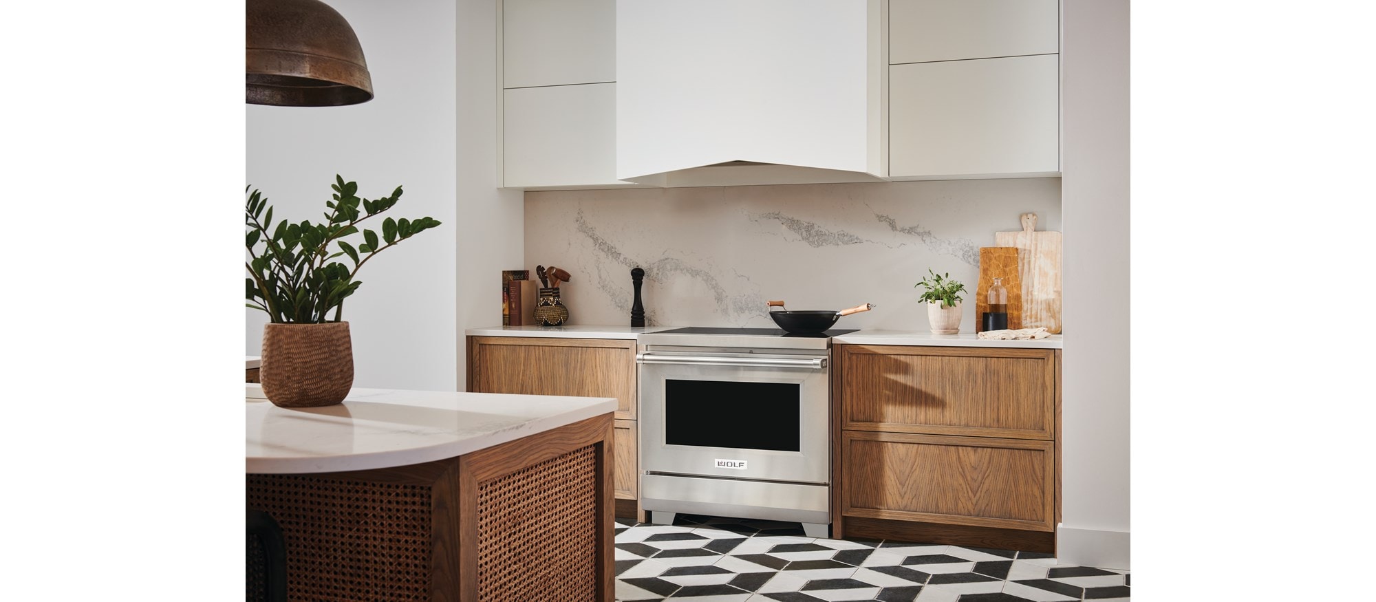 Wolf 36" Professional Induction Range (IR36550/S/P) with white Wolf Wall Hood featured in modern kitchen with black and white tile flooring.