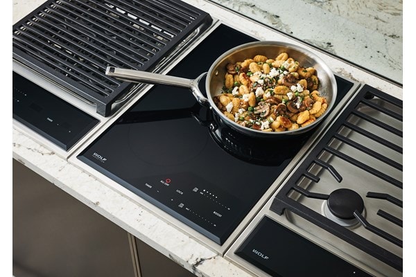 Wolf 15" transitional induction cooktop module (CI152TFS) paired with a 15" transitional grill module (GM15TFS) and 15" transitional gas cooktop module (CE152TFS)