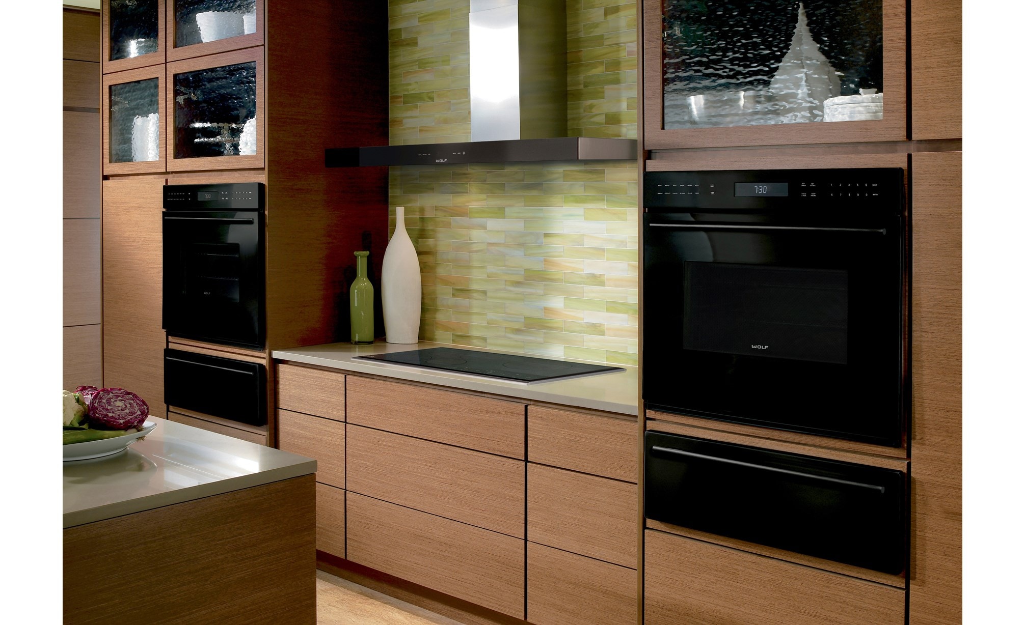 The Wolf 45" Cooktop Wall Hood - Black (VW45B) shown with a variety of Wolf cooking appliances in warm contemporary kitchen