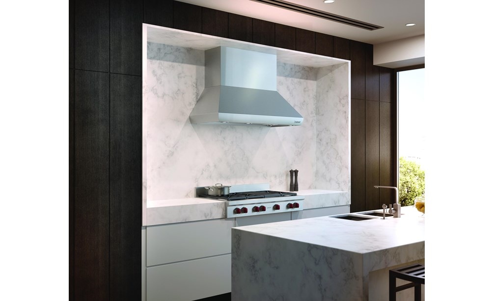 The Wolf 54" Pro Wall Chimney Hood (PWC542418) shown here framed expertly in a rich marble backsplash is the crown jewel of any kitchen 