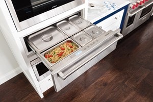 The Wolf 30" Warming Drawer (WD30) displaying it's capacity for holding several dishes while looking great with dark wood floors