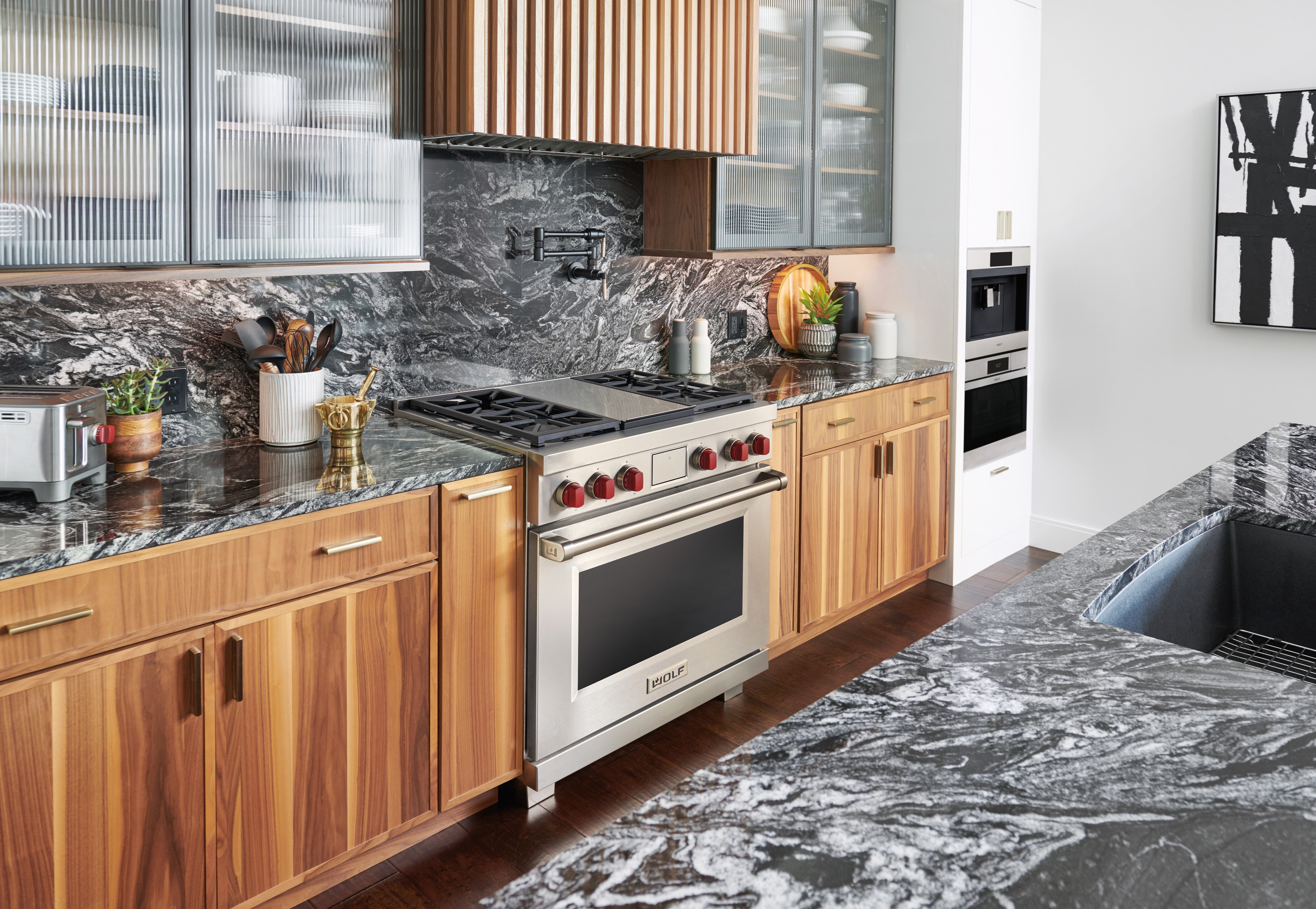 Wolf 36" Dual Fuel Range displayed in a modern kitchen condo design featuring custom cabinetry and rich marble countertops.
