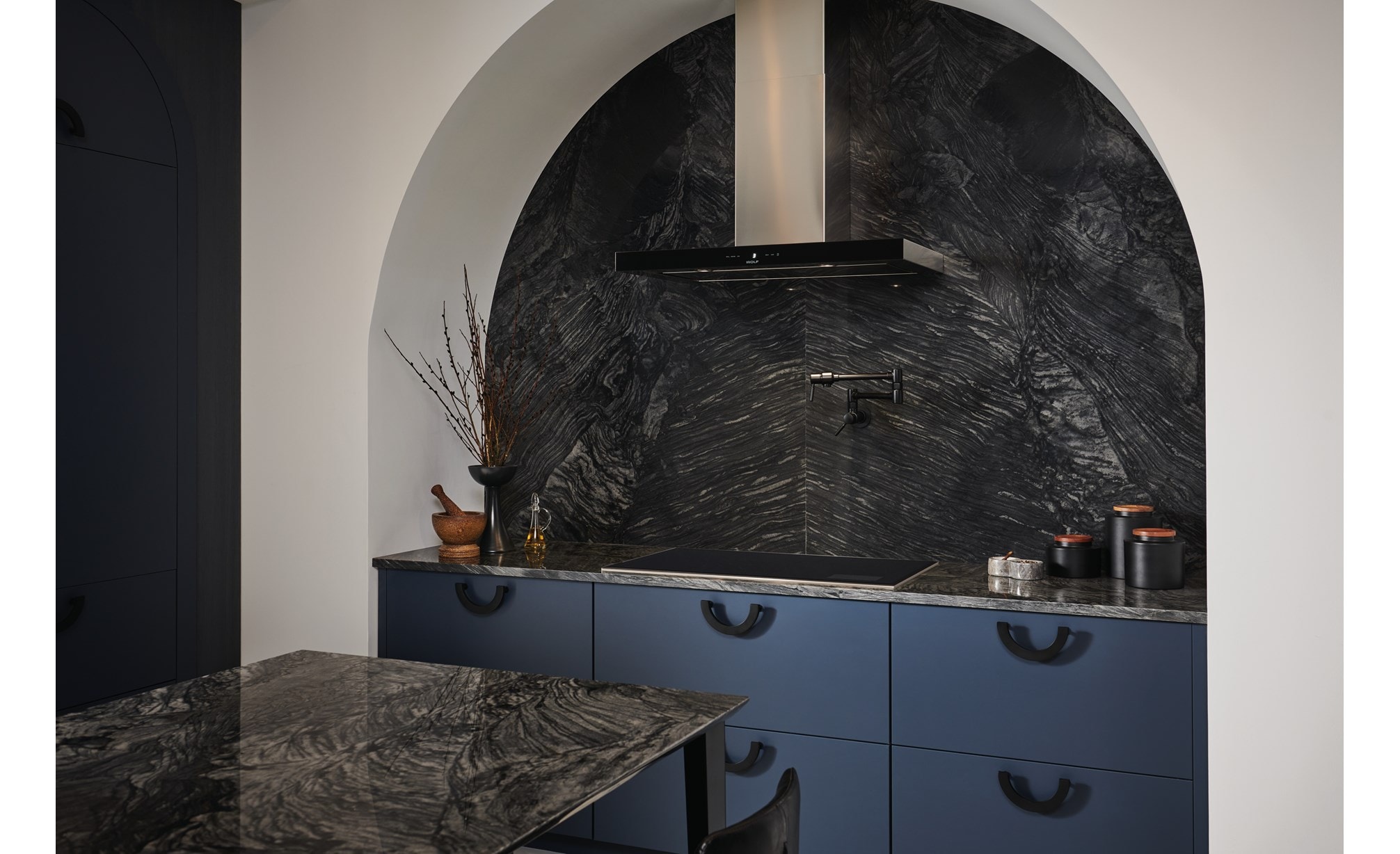 Wolf 36" Transitional Induction Cooktop (CI36560T/S) featured in marble arch cooking enclosure with blue cabinet drawers. 