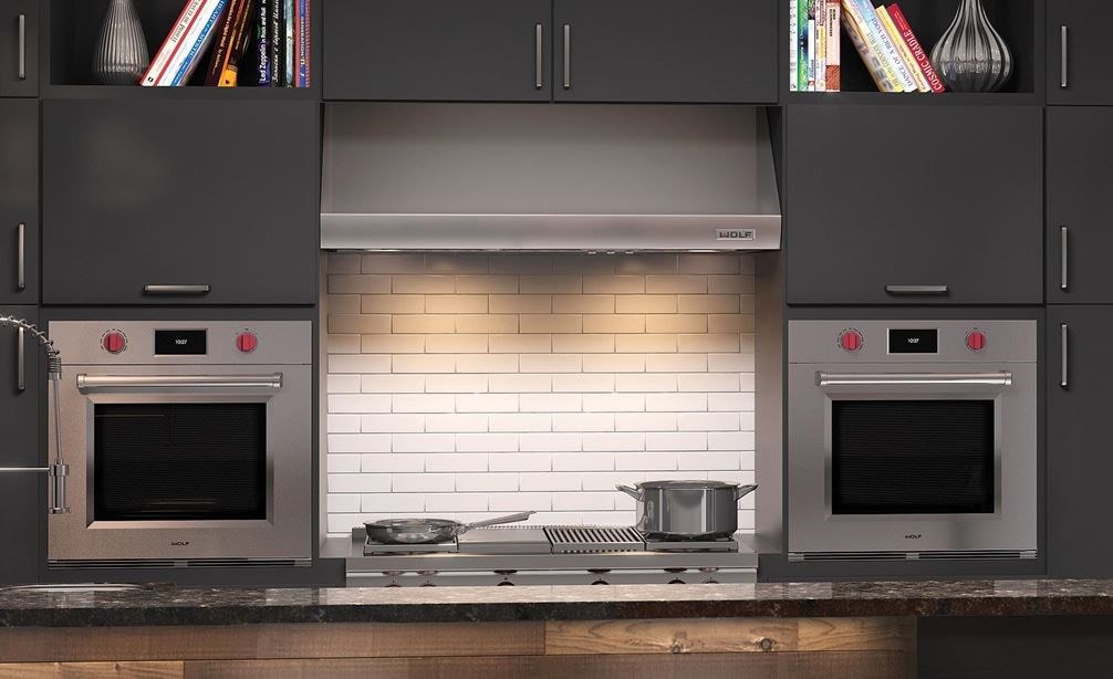 Wolf 30&quot; M Series Professional Single Ovens (SO30PM/S/PH) shown on each side of a Wolf 48&quot; Pro Wall Hood - 24&quot; Depth (PW482418)