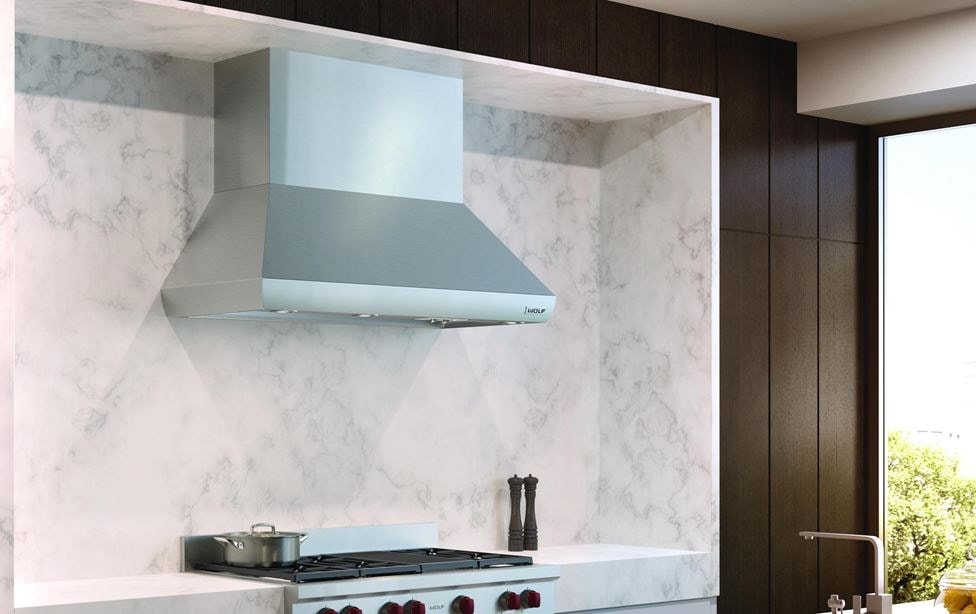 The Wolf 54&quot; Pro Wall Chimney Hood (PWC542418) shown here framed expertly in a rich marble backsplash is the crown jewel of any kitchen 