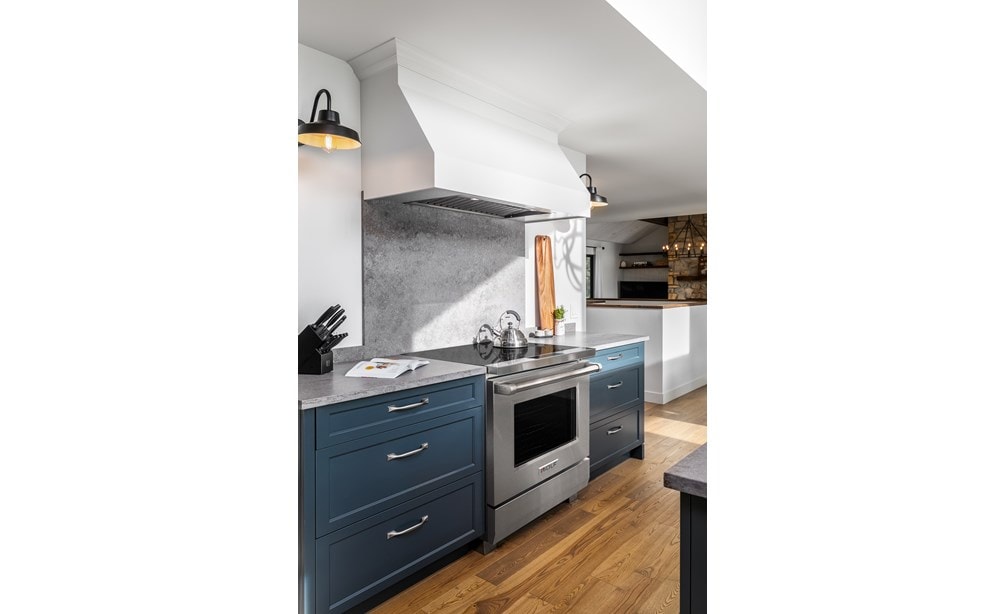 Wolf 30" Professional Induction Range (IR30450/S/P) with a white Wolf Wall Hood featured in navy blue cabinetry.