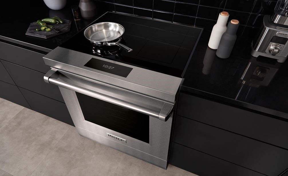 Wolf 30" Professional Induction Range (IR30450/S/P) featured in matte black cabinetry with a stainless steel pan set on its black ceramic glass surface.
