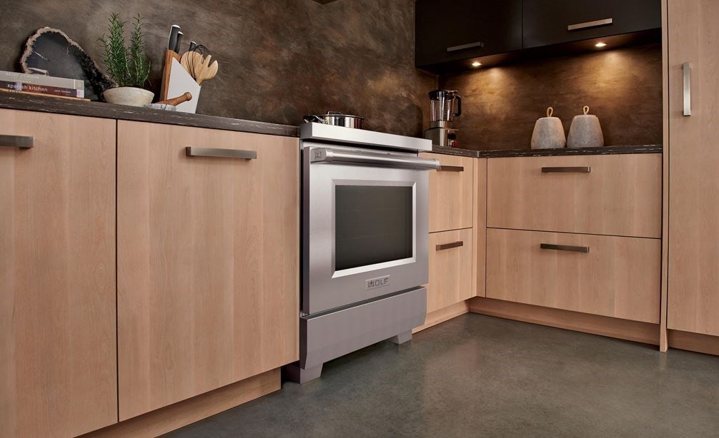 Wolf 30" Professional Induction Range (IR30450/S/P) featured in light brown cabintry next to a Wolf Gourmet Blender.