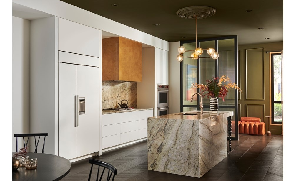 Dans cette cuisine moderne à l'audace architecturale, le réfrigérateur-congélateur Sub-Zero côte-à-côte Classic 42 po, prêt à recevoir un panneau personnalisé, dialogue parfaitement avec les armoires blanches et se fond dans un ensemble de granit élégant