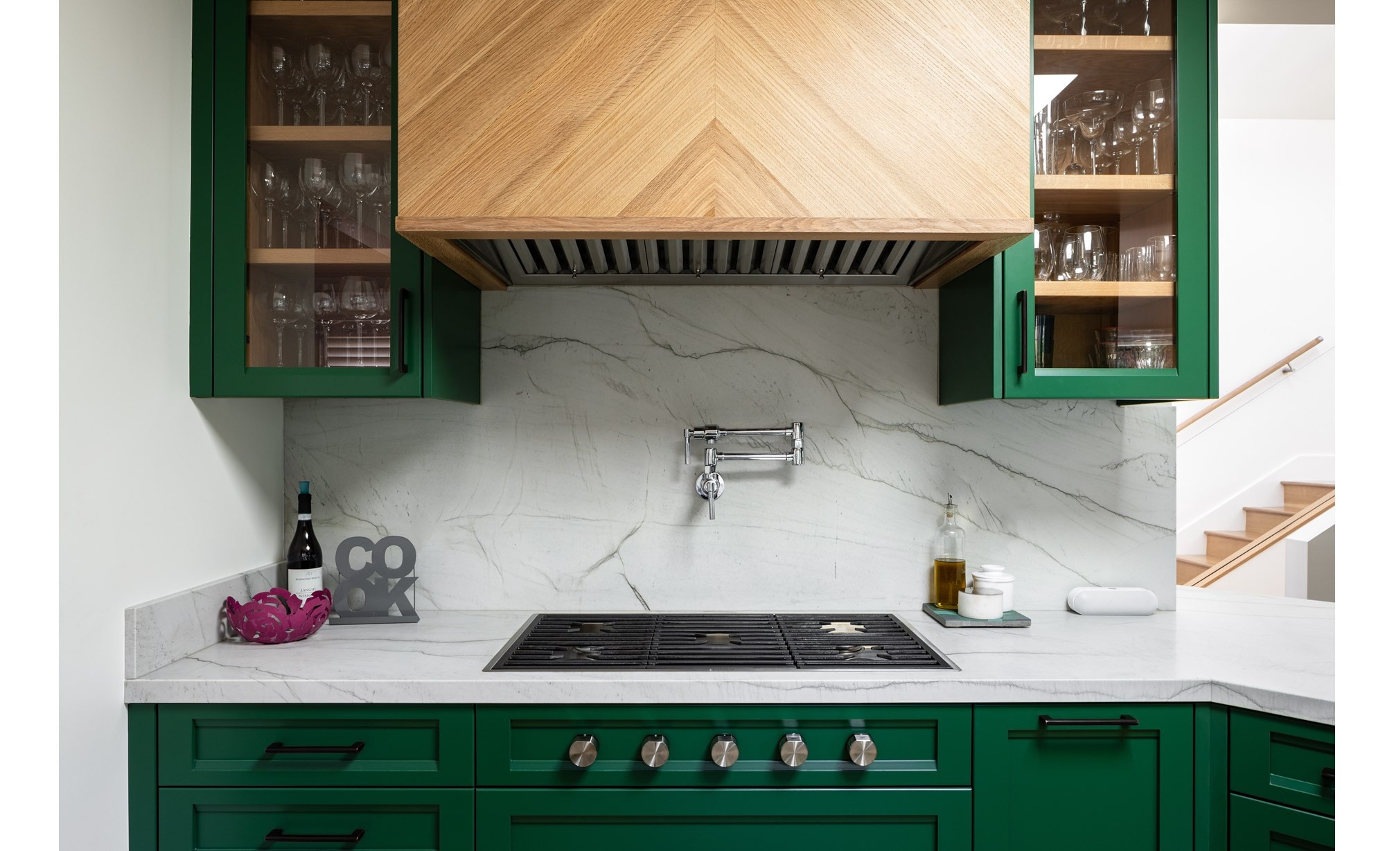 Wolf 36-inch contemporary gas cooktop featured in small space stylish kitchen with green cabinets and marble backsplash.