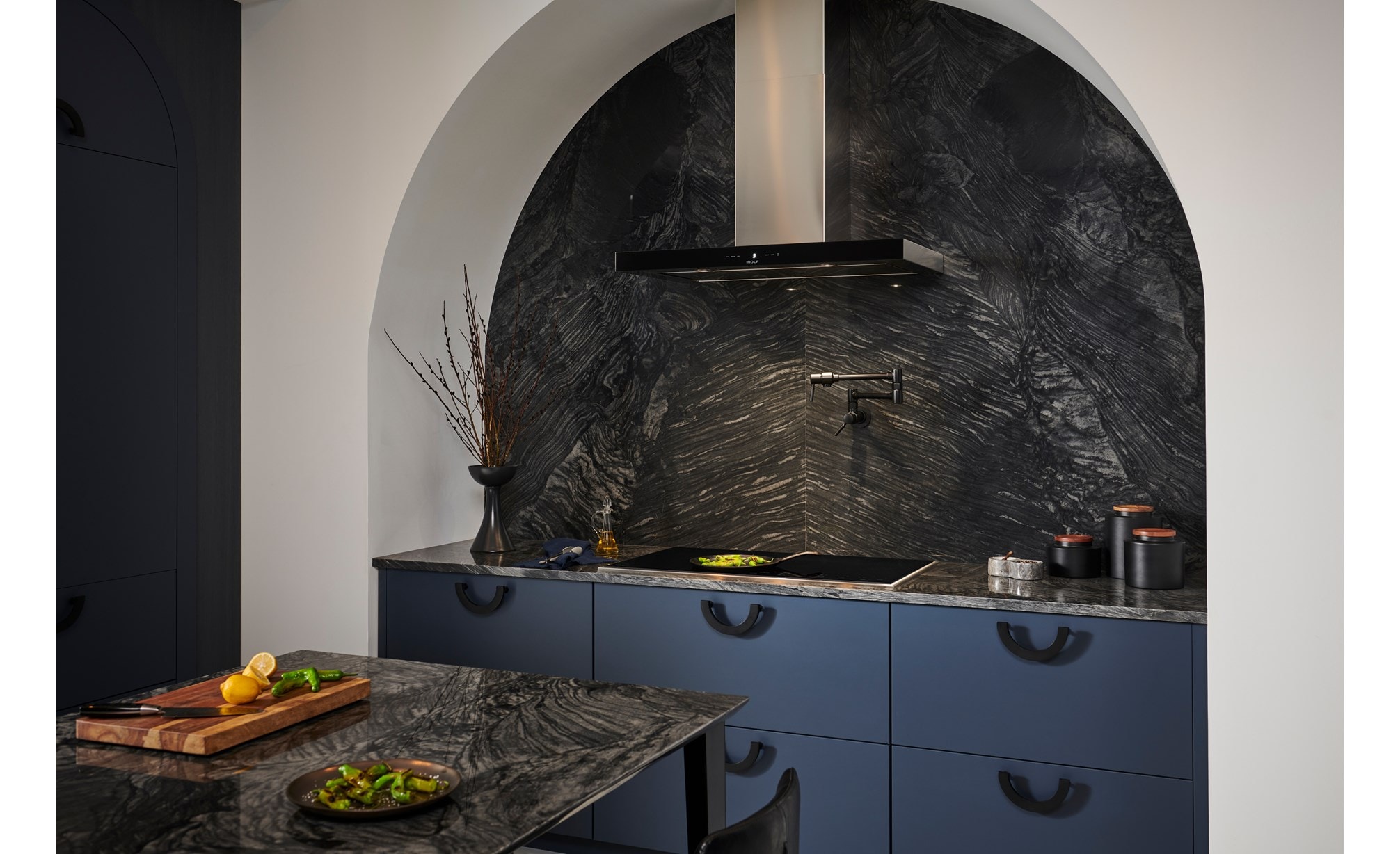 Surface de cuisson Wolf à encadrement de style transitionnel (CI365TF/S) présentée dans une cuisine en arc de cercle personnalisée avec un comptoir en marbre gris et un dosseret personnalisé.