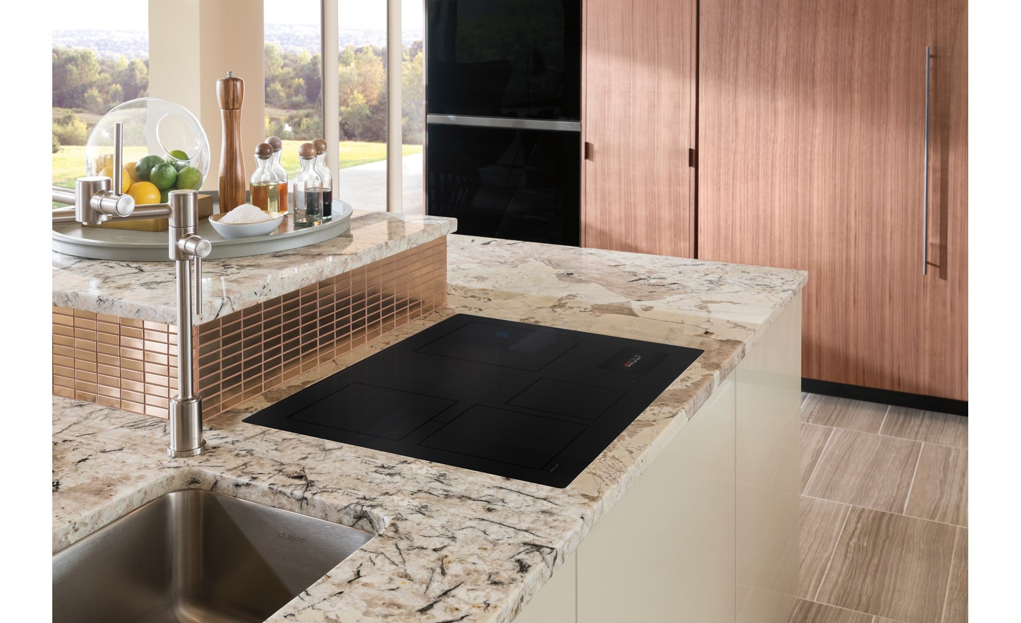 Surface de cuisson à induction Wolf 30 po de style contemporain, montée encastrée dans un comptoir de cuisine en marbre gris et blanc.