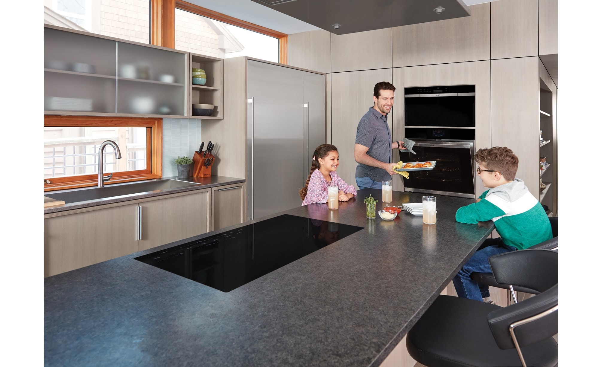 La surface de cuisson à induction Wolf 36 po de style contemporain (CI365C/B) présentée dans un très grand bar d'îlot de cuisine est très efficace et exceptionnellement sûre