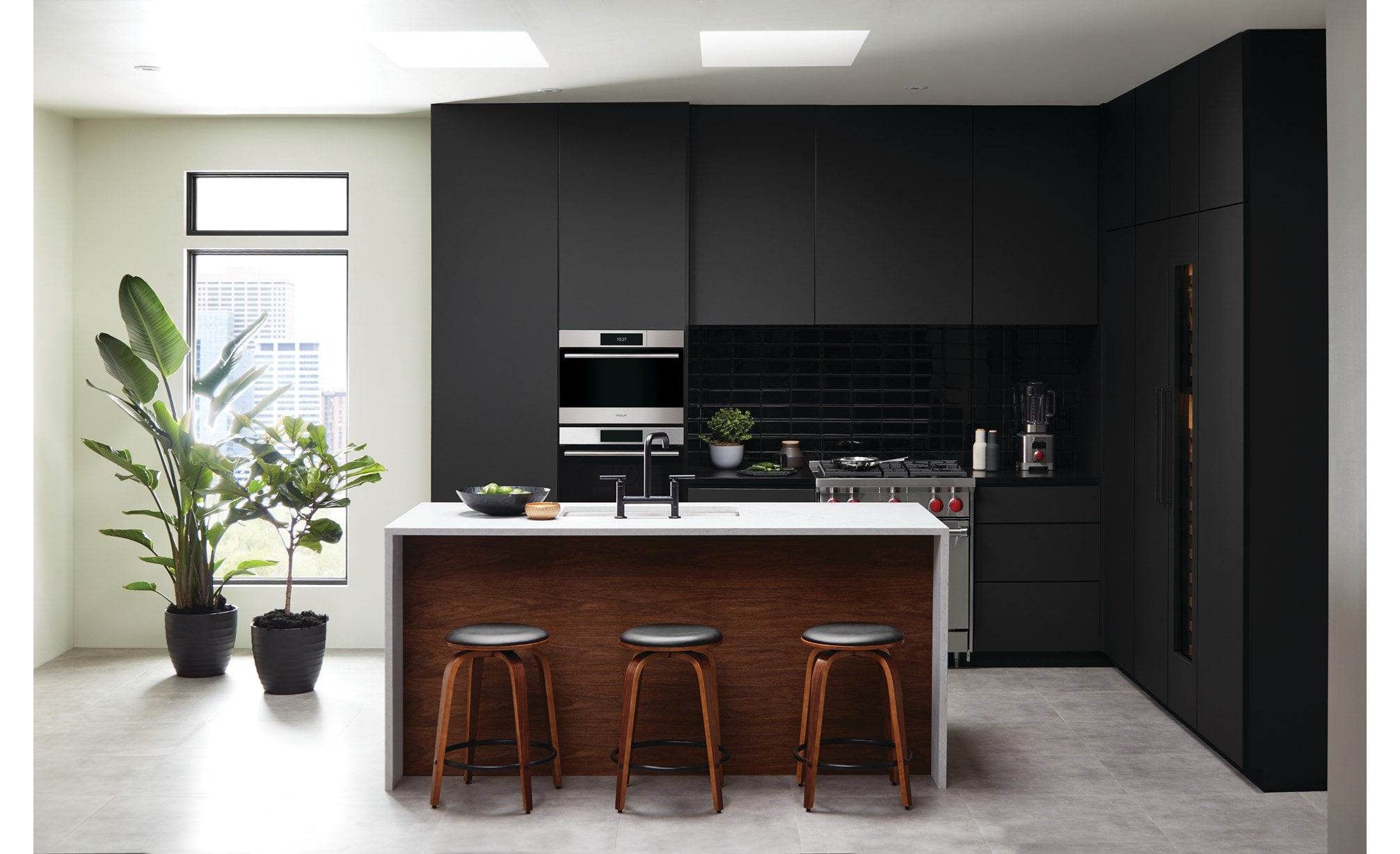 Four à convection-vapeur de style transitionnel de Wolf Série E 24 po (CSO2450TE/S/T) entouré d'armoires noires dans une cuisine d'appartement éclairée par le soleil