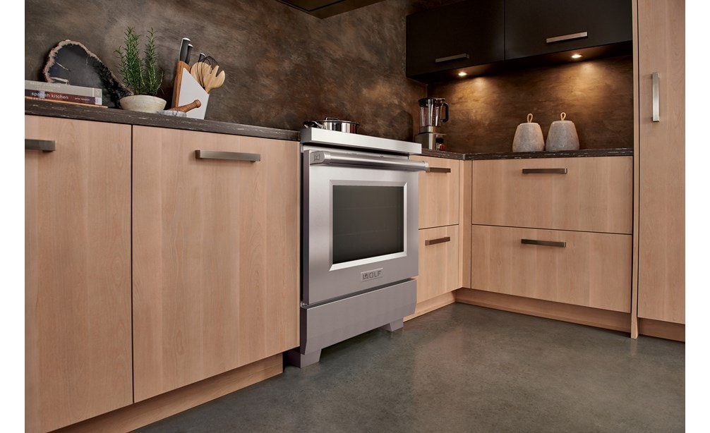 Cuisinière à induction Wolf 30/34 de style professionnel (IR30450/S/P) présentée dans une armoire marron clair à côté d'un mixeur Wolf Gourmet.