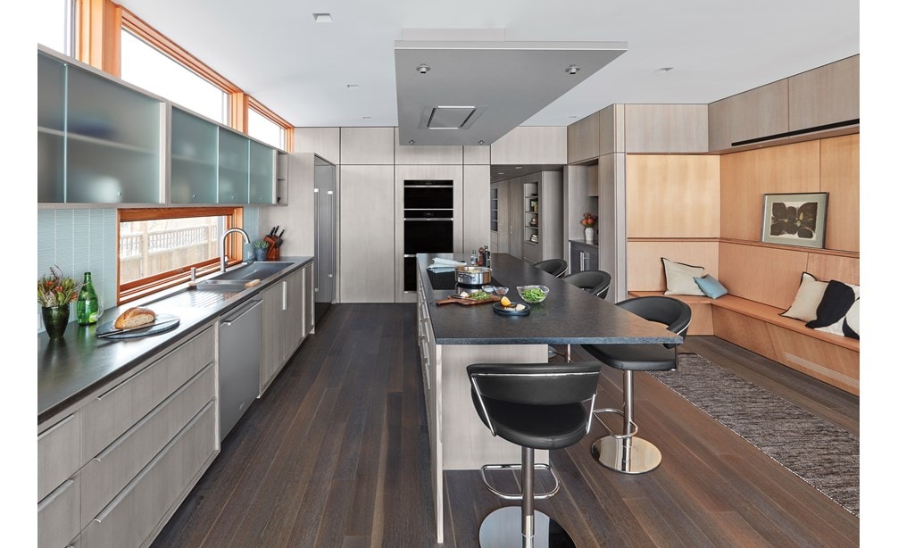 Hotte installée au plafond Wolf de 36 po en acier inoxydable (VC36S) qui se fond parfaitement au-dessus d'un grand îlot dans une cuisine minimaliste moderne