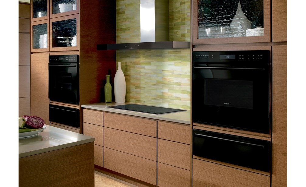 La hotte murale Wolf 45 po pour surface de cuisson - noire (VW45B) est présentée avec une variété d'appareils de cuisson Wolf dans une cuisine contemporaine chaleureuse