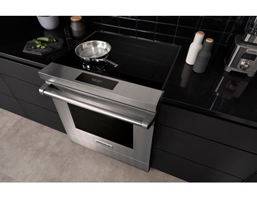 La surface de cuisson à induction moderne de 36 po de Wolf (CI36560T), avec son élégante surface en verre noir épuré, s'intègre en affleurant parfaitement dans cette cuisine contemporaine à l'ambiance méditerranéenne.