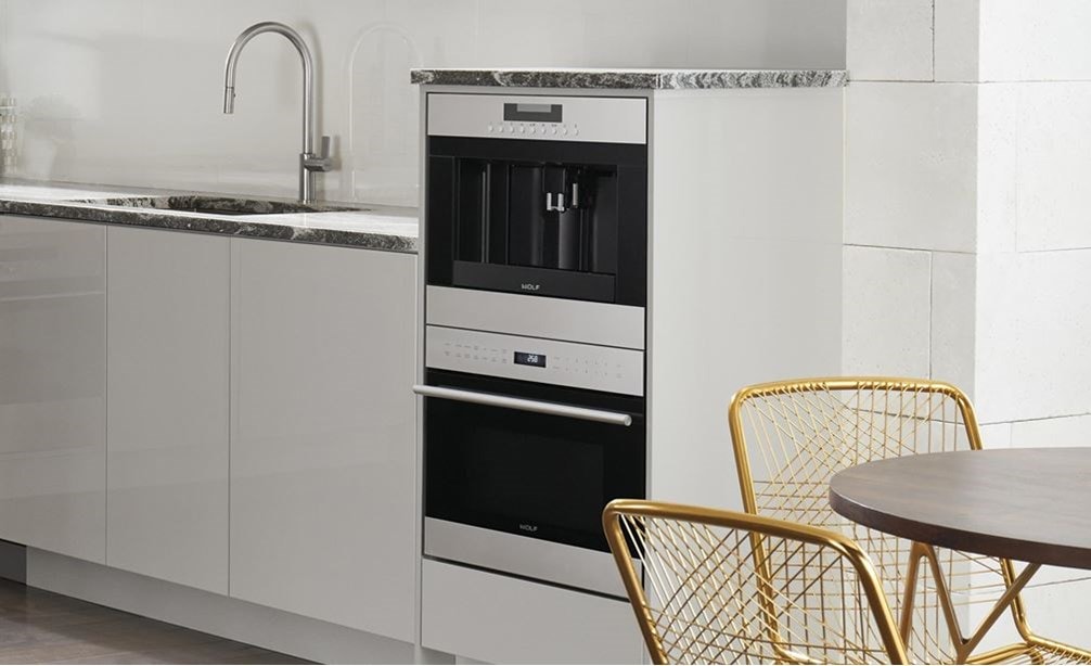 Le système à café Wolf 24 po en acier inoxydable (EC24/S) est présenté dans une cuisine contemporaine élégante avec des armoires lisses sans poignée