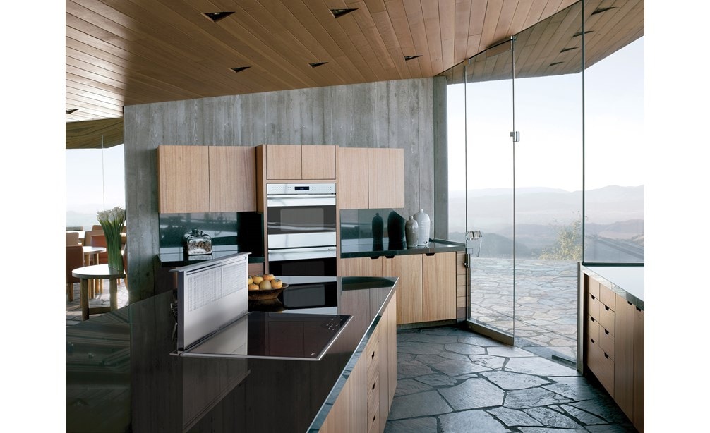 La surface de cuisson à induction Wolf 36 po de style transitionnel (CI365T/S) présentées avec une ventilation à tirage descendant de 36 po (DD36) dans de grands comptoirs en granit riche