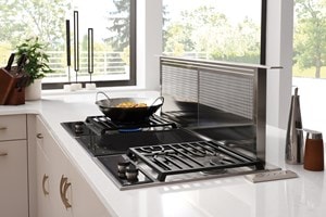 La surface de cuisson à induction Wolf 15 po de style transitionnel (CI152TF/S) présentée en affleurement dans un comptoir de granit artistique moucheté de noir et de blanc
