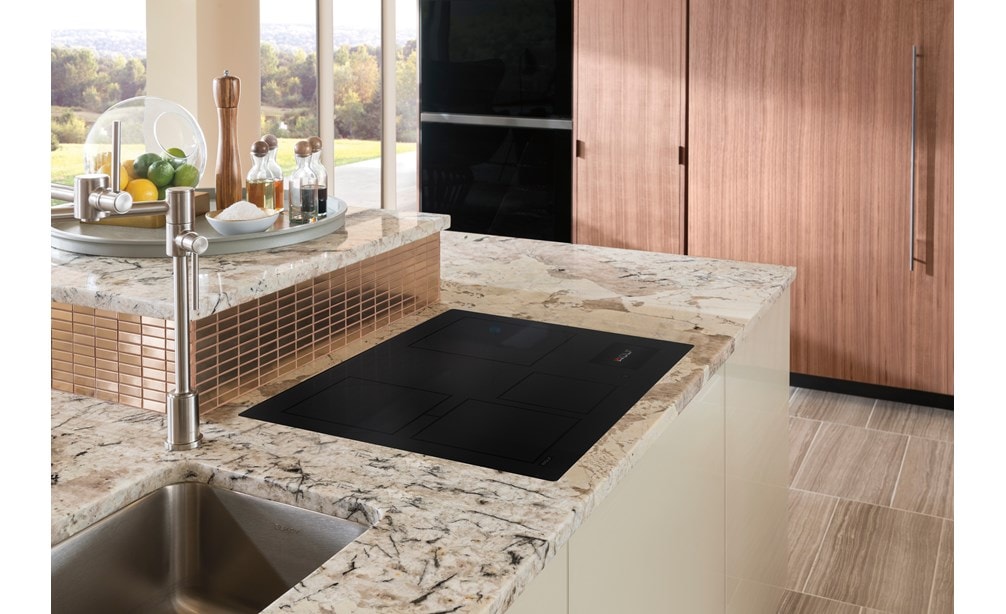 Surface de cuisson à induction Wolf 30 po de style contemporain, montée encastrée dans un comptoir de cuisine en marbre gris et blanc.