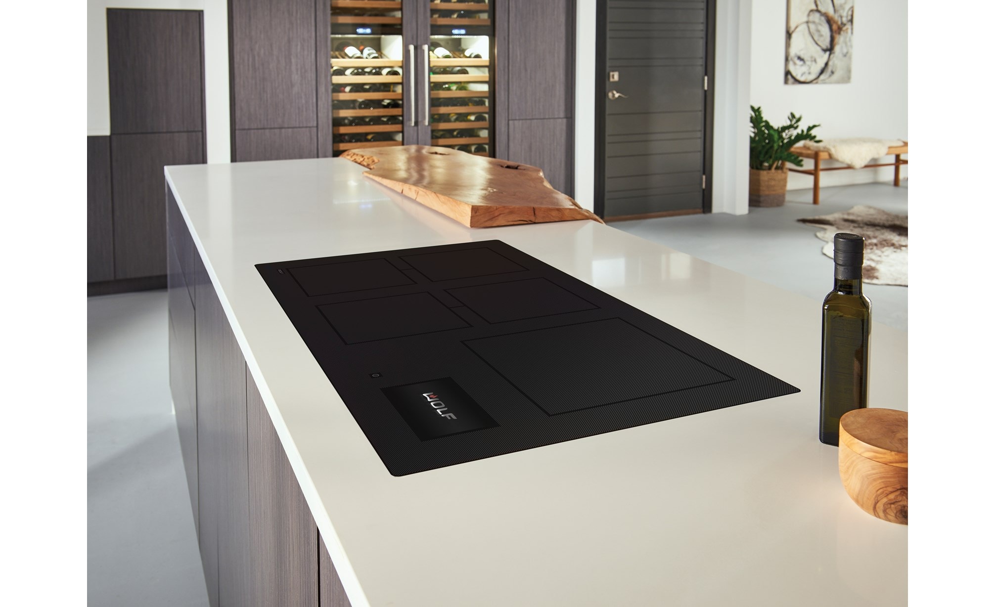 Surface de cuisson à induction Wolf 36 po de style contemporain (CI36560C/B) présentée dans une cuisine moderne, se fondant parfaitement dans les plans de travail blancs lisses et les armoires aux tons de bois chauds.