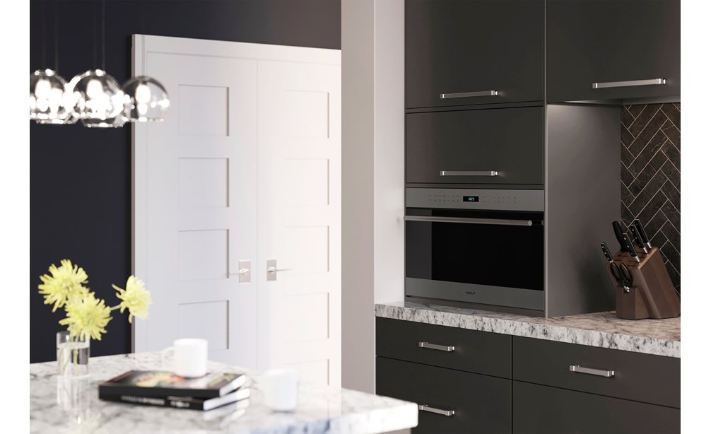 Four à micro-ondes Wolf 30 po série E à porte s'ouvrant vers le bas de style transitionnel (MDD30TE/S/TH) placé de façon experte dans un meuble lisse avec dosseret gris